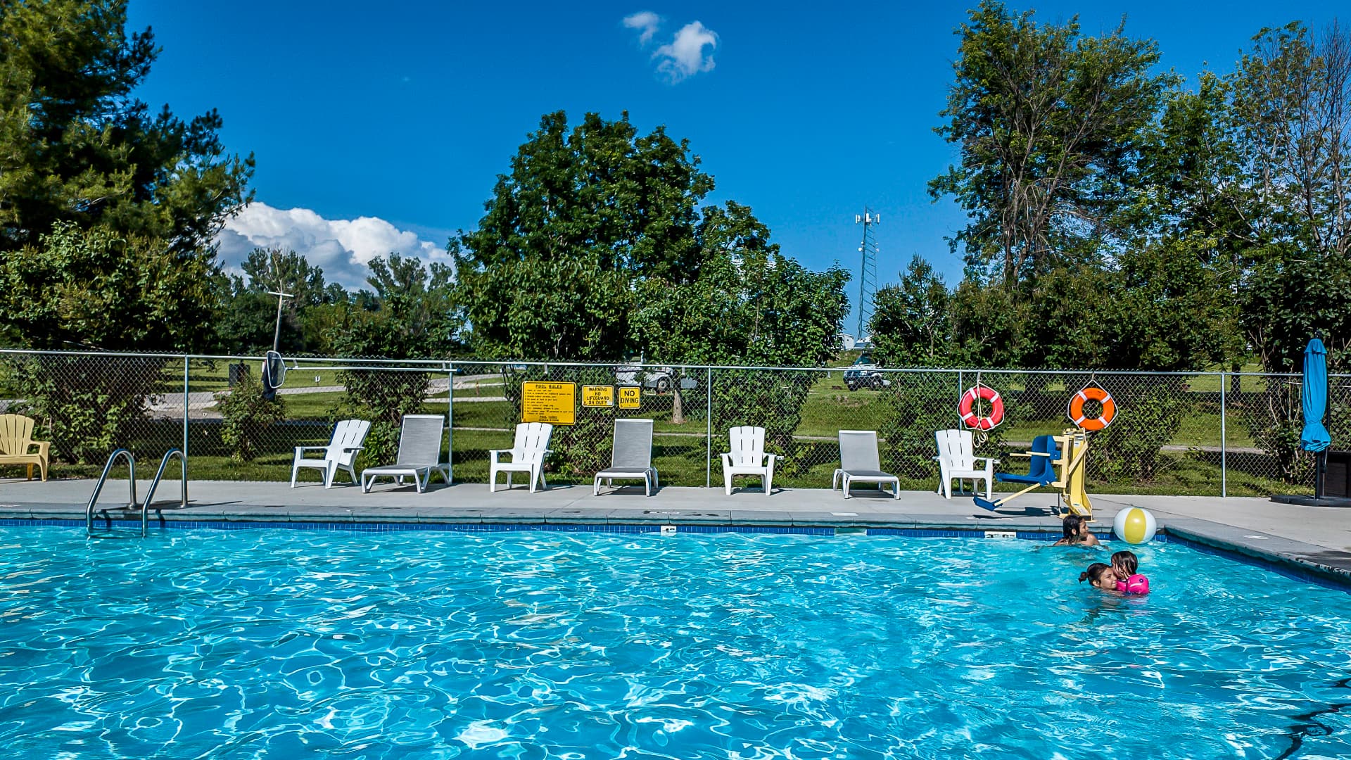 Swimming pool surrounded by lounge chairs on a bright summer day