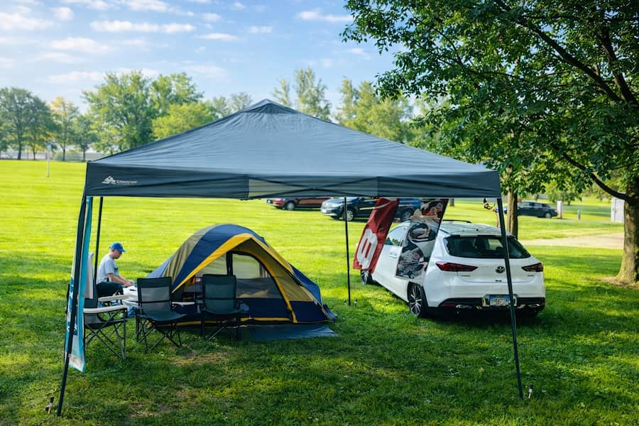 Tent site with canopy, camping chairs, and car parked on a grassy site at Alta Campground