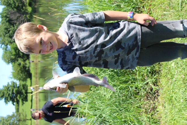 Young camper showing off a catch from the stocked pond